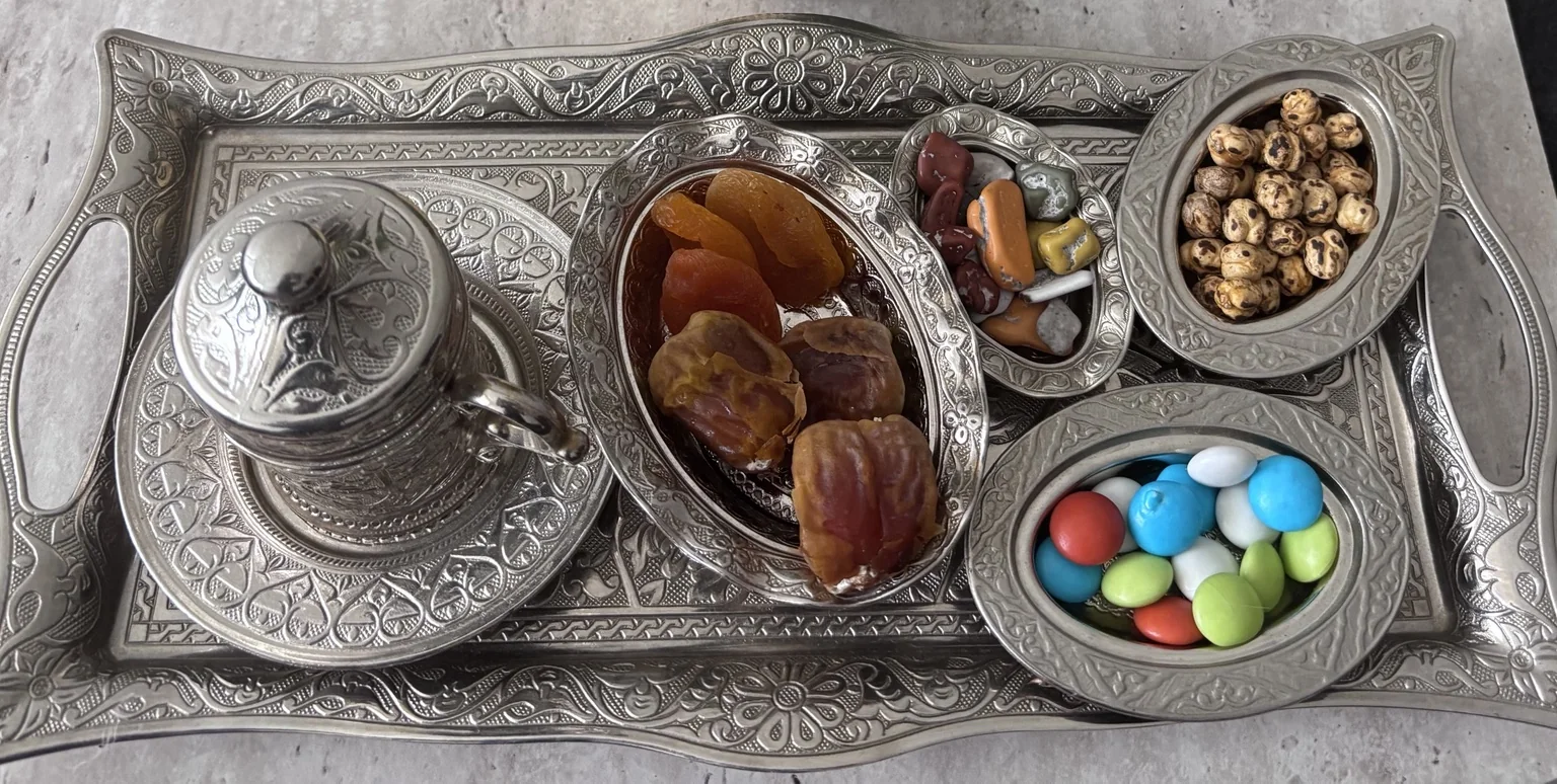 Kapağı kapalı kahve fincanı ve ikramların yakından görünümü.